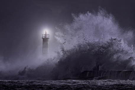 waves dashing against lighthouse on cliffs
