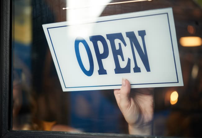 hand turning shop sign to 'open'