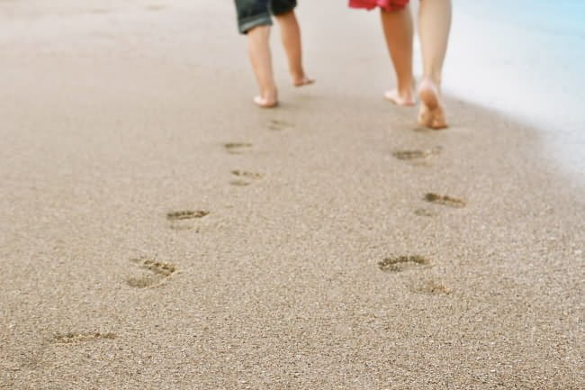 parent and child walk across the beach