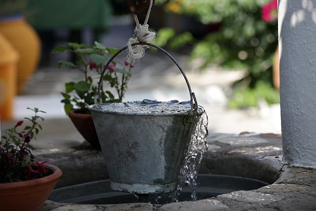 overflowing bucket drawn from a well