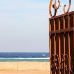 rusty gate opening to view of beach and sea