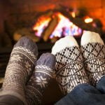 two pairs of woolly-socked feet warming at the fire