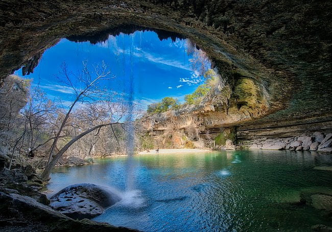 mouth of a cave with lake stretching out into sunlight