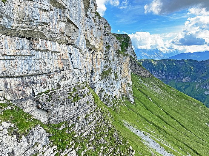 eroding rockface and green slopes below